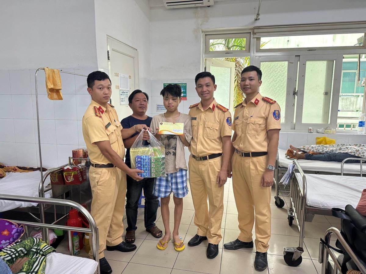 Đại diện Trạm Cảnh sát giao thông Hòa Nhơn trao tiền hỗ trợ cho em Bảo.