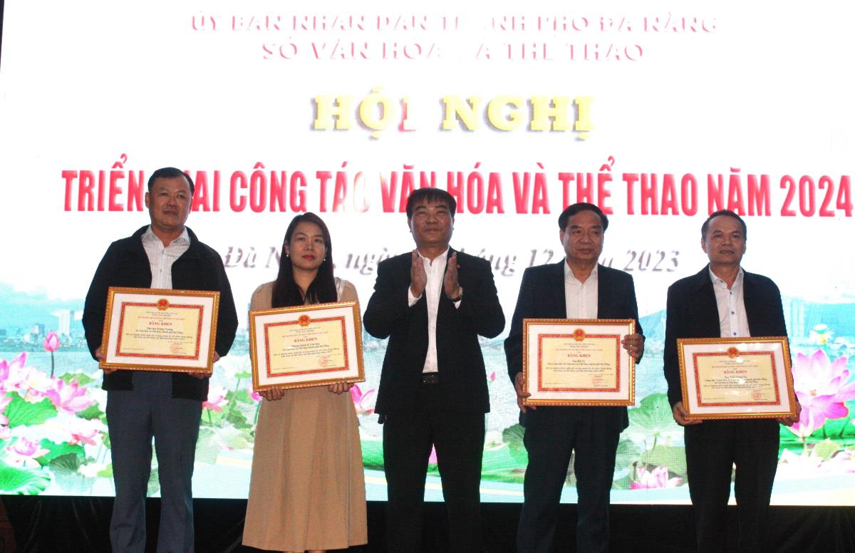 Thừa ủy quyền, ông Hà Vỹ (trái)- Phó Giám đốc Sở VH-TT trao Bằng khen của Thủ tướng Chính phủ cho Phòng Quản lý TDTT.