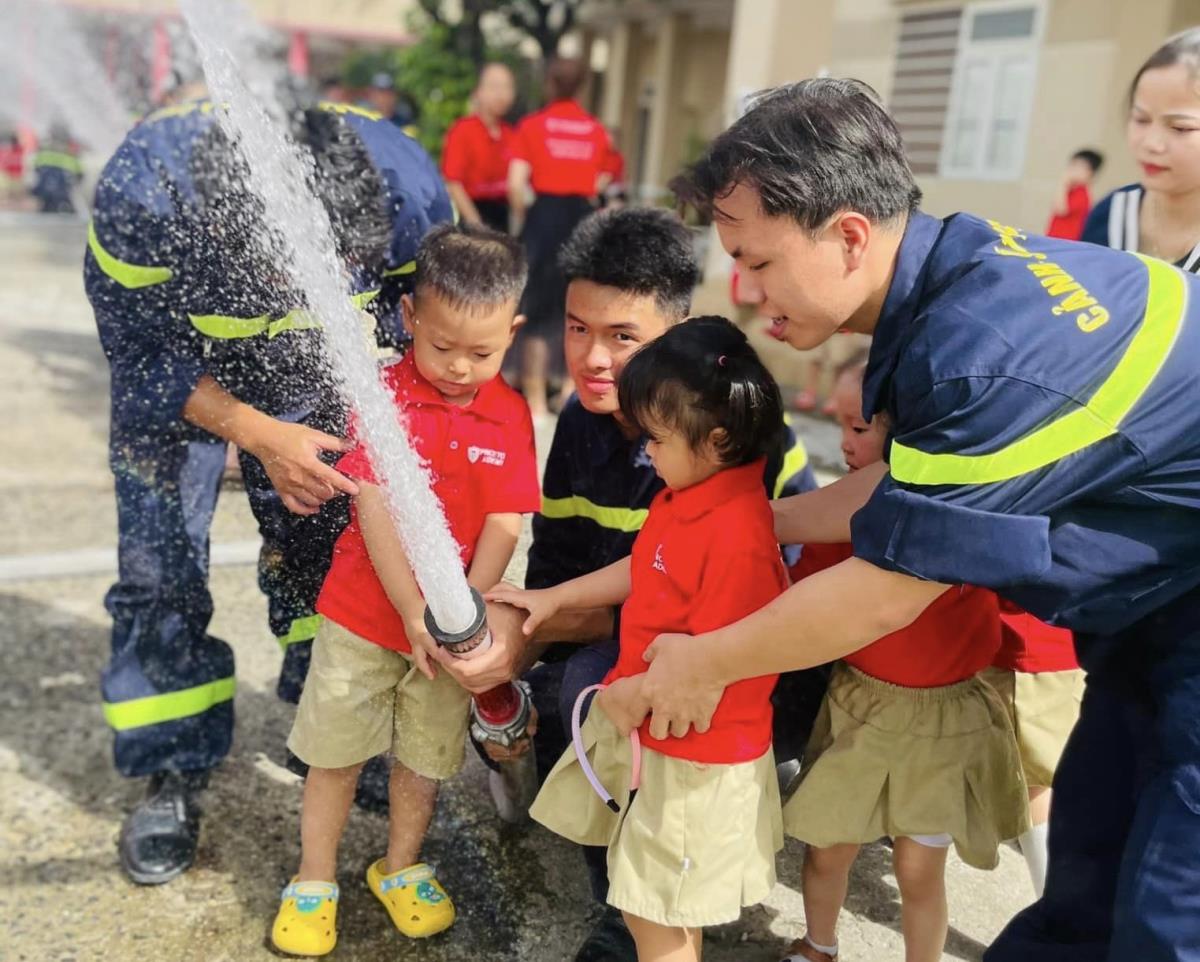 Công an quận Cẩm Lệ hướng dẫn các em học sinh Cơ sở Mầm non Học Viện Hoàng Tử động tác phun nước chữa cháy.