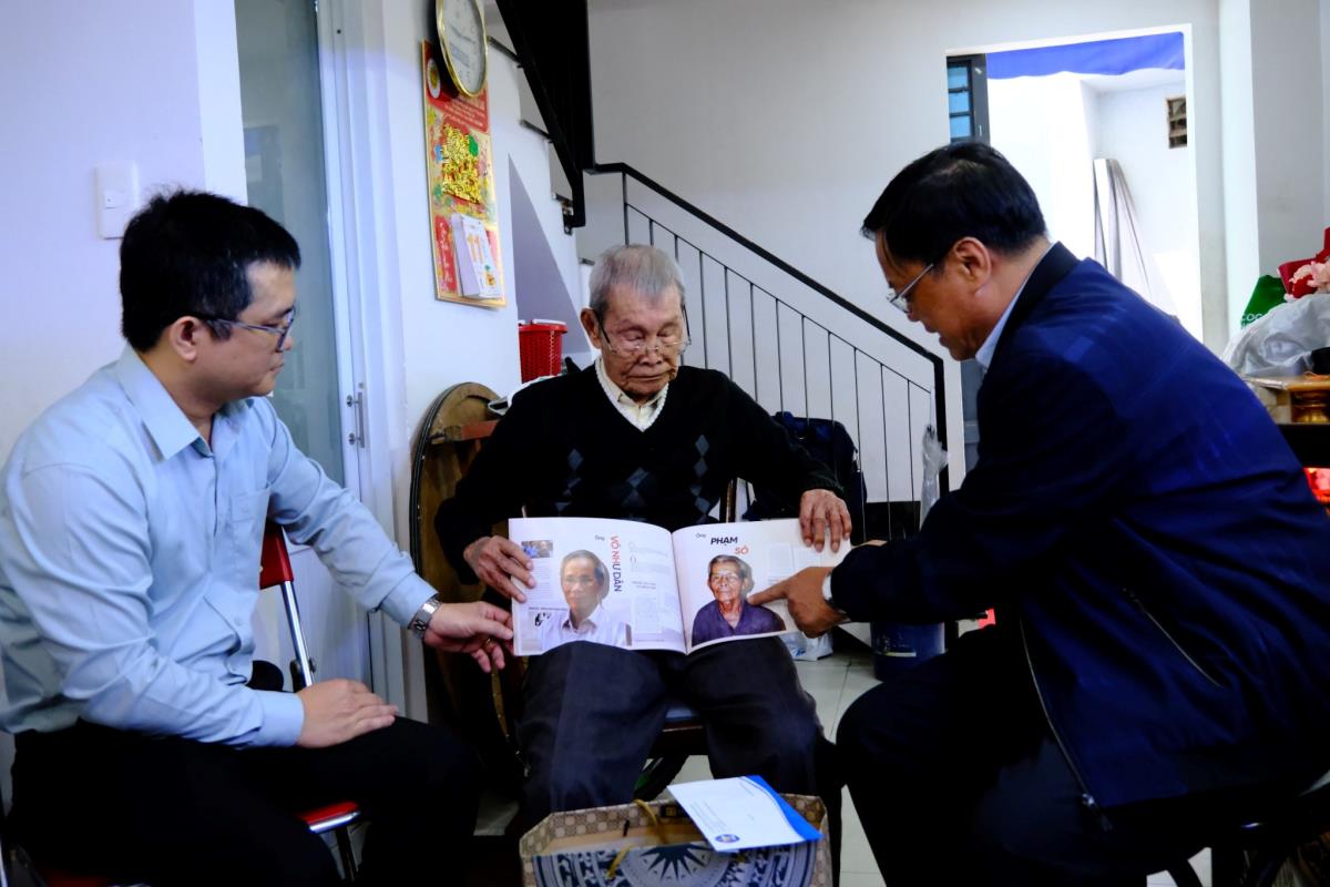 Ông Phạm Sô (ngồi giữa) - nhân chứng Hoàng Sa nhận cuốn tư liệu từ Chủ tịch UBND huyện Hoàng Sa Võ Ngọc Đồng.