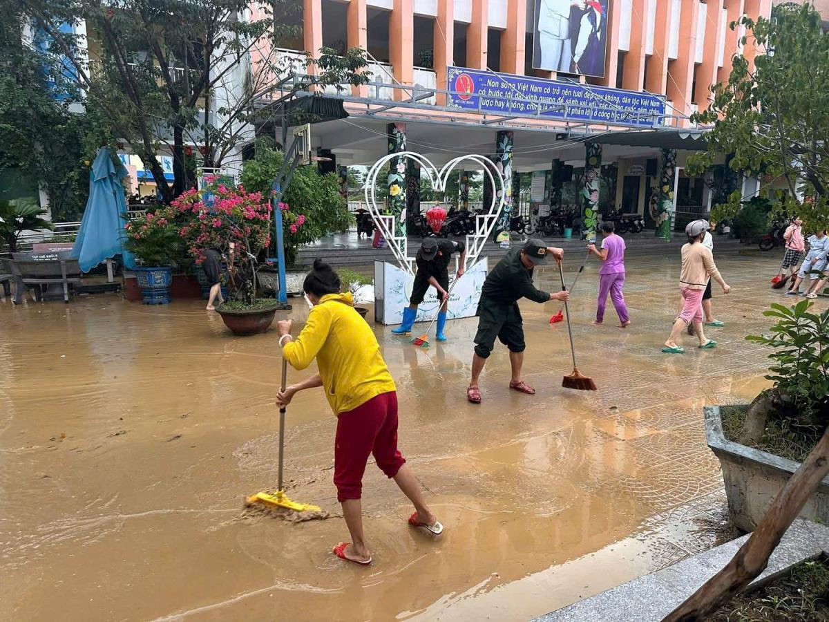 Lực lượng Công an sử dụng vòi chuyên dụng rửa sân trường tại các điểm trường bị ngập sâu.