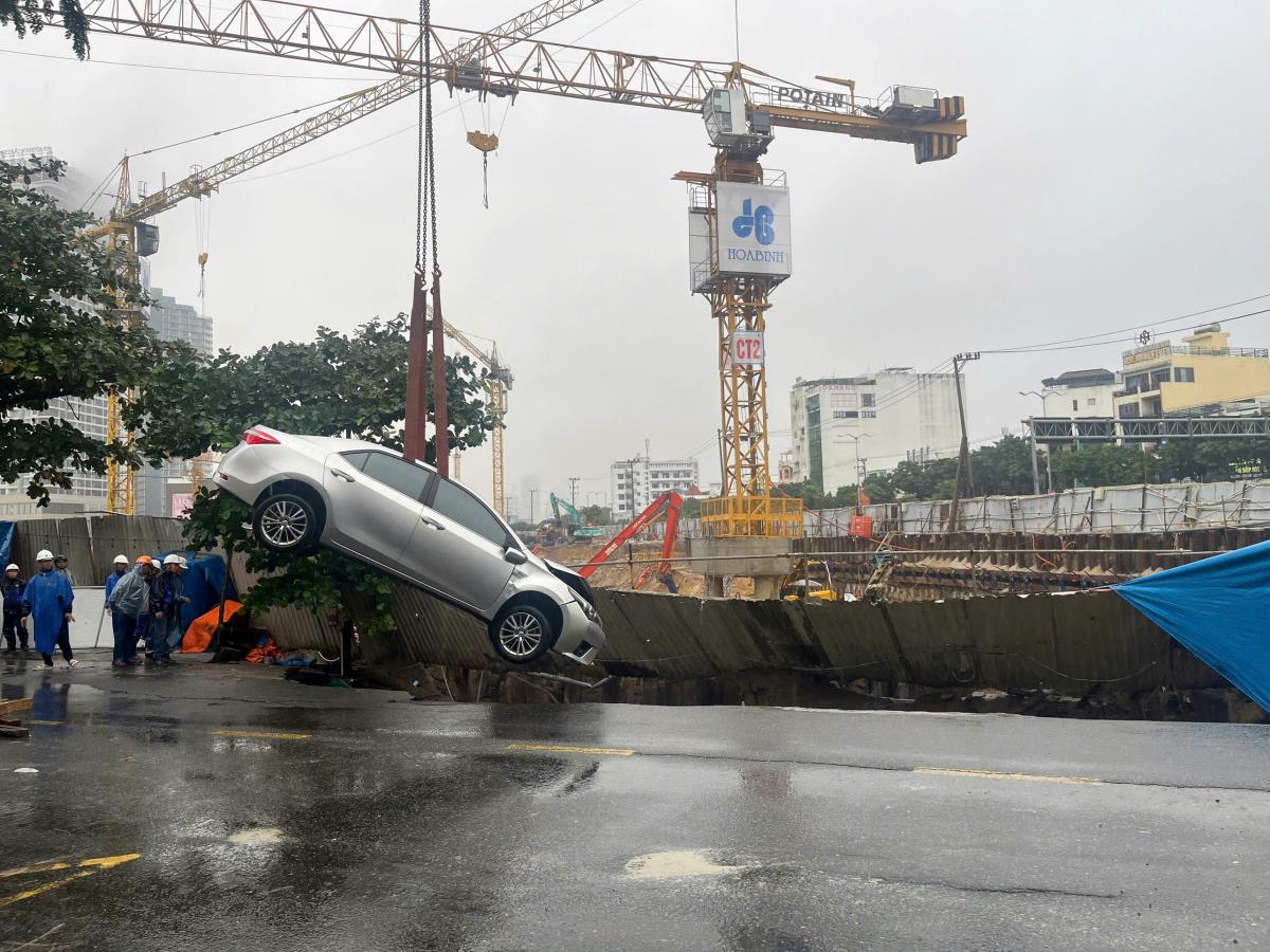 Lực lượng chức năng đang cẩu chiếc xe rơi xuống hố lên.