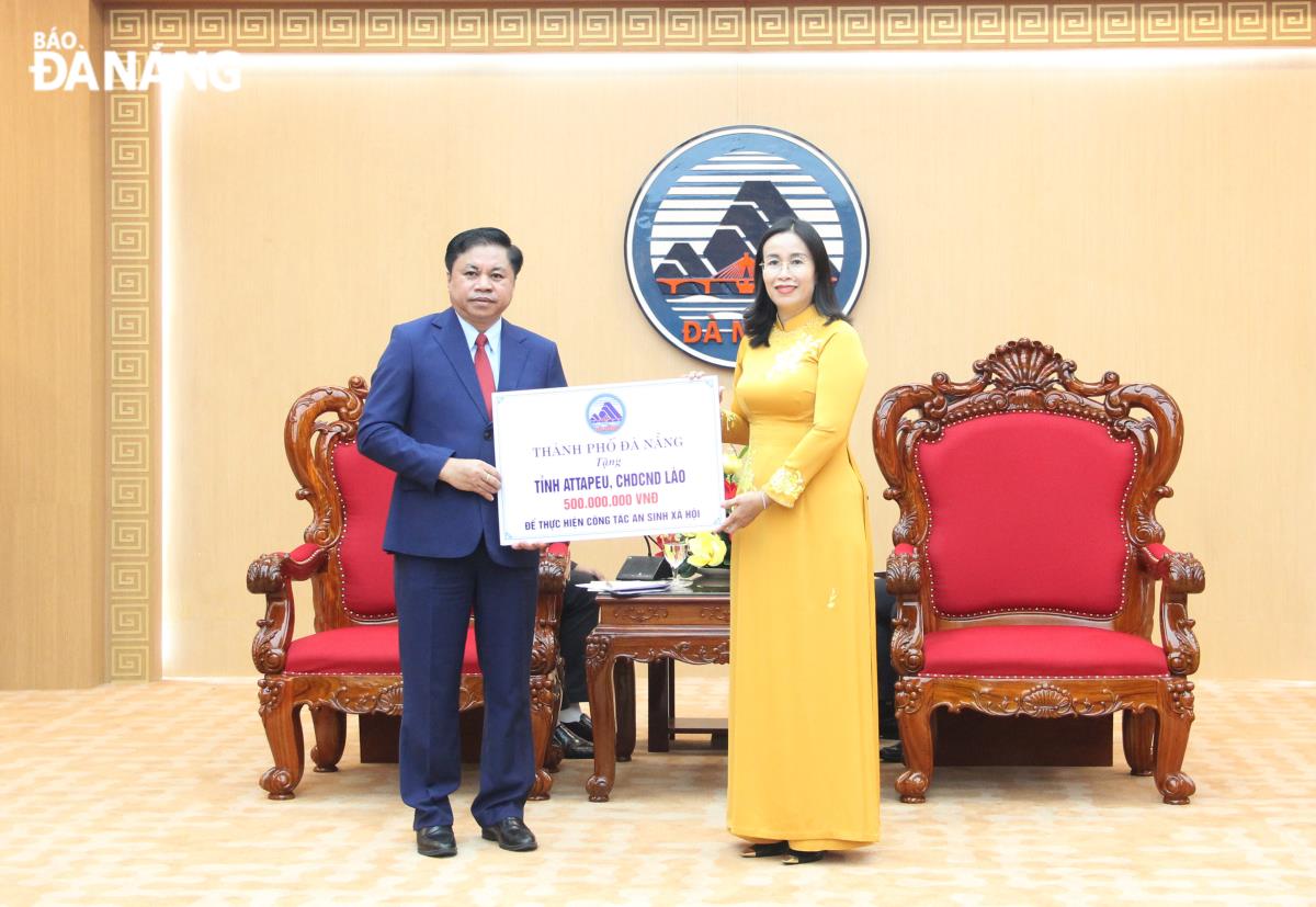 Phó Chủ tịch UBND thành phố Nguyễn Thị Anh Thi (bên phải) trao hỗ trợ kinh phí 500 triệu đồng thực hiện công tác an sinh xã hội tại tỉnh Attapeu.