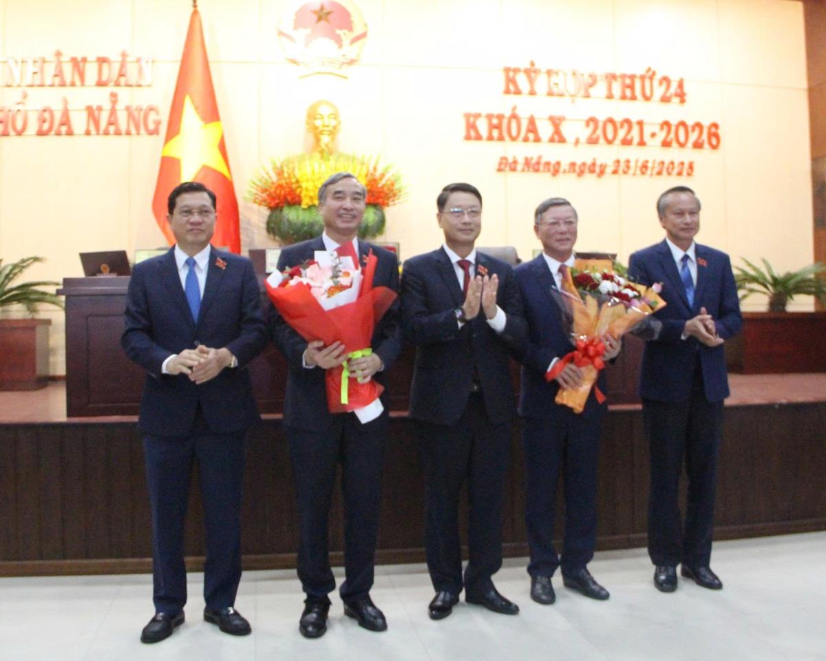 Lãnh đạo HĐND TP tặng hoa cho đồng chí Lê Trung Chinh (thứ hai từ trái qua) và ông Lê Văn Trung (thứ hai từ phải qua).