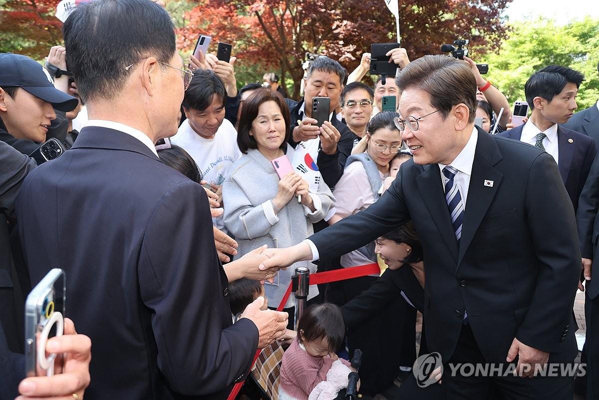 Tổng thống Lee Jae-myung (phải) bắt tay những người ủng hộ khi ông rời khỏi dinh thự của mình ở Incheon, phía tây Seoul, vào ngày 4-6.
Ảnh: Yonhap