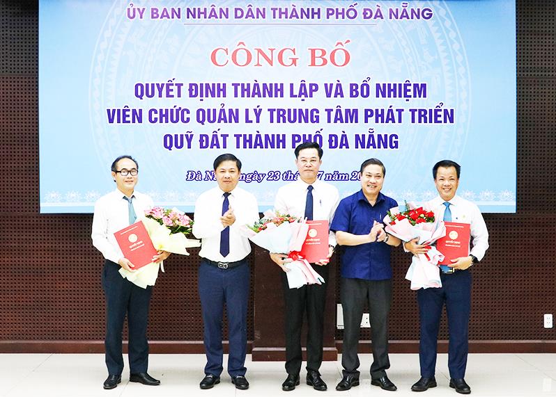 Chủ tịch UBND TP Đà Nẵng Lương Nguyễn Minh Triết và Phó Chủ tịch UBND thành phố Phan Thái Bình cùng trao quyết định, tặng hoa chúc mừng Ban lãnh đạo Trung tâm Phát triển quỹ đất TP Đà Nẵng.