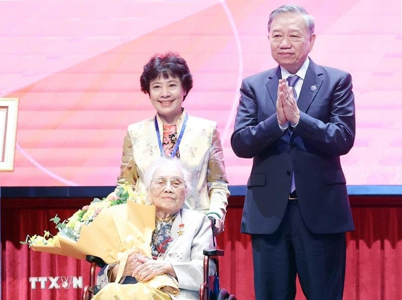 Tổng Bí thư Tô Lâm trao danh hiệu Anh hùng Lao động và tặng hoa chúc mừng nguyên Phó Chủ tịch nước Nguyễn Thị Bình. Ảnh: TTXVN