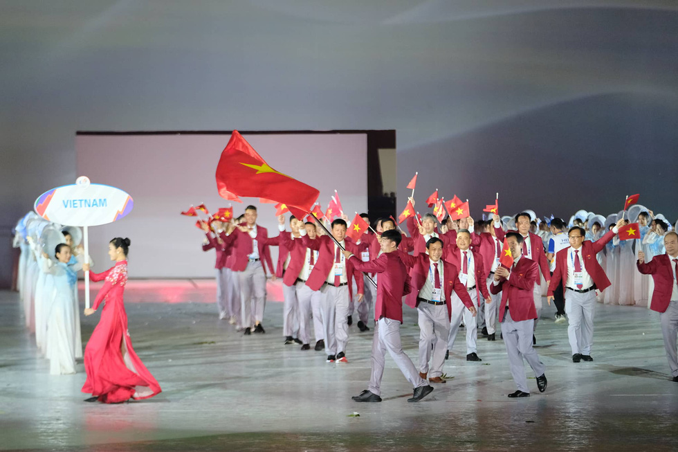 VĐV Nguyễn Huy Hoàng cầm cờ dẫn đầu Đoàn thể thao Việt Nam - Ảnh: NAM TRẦN