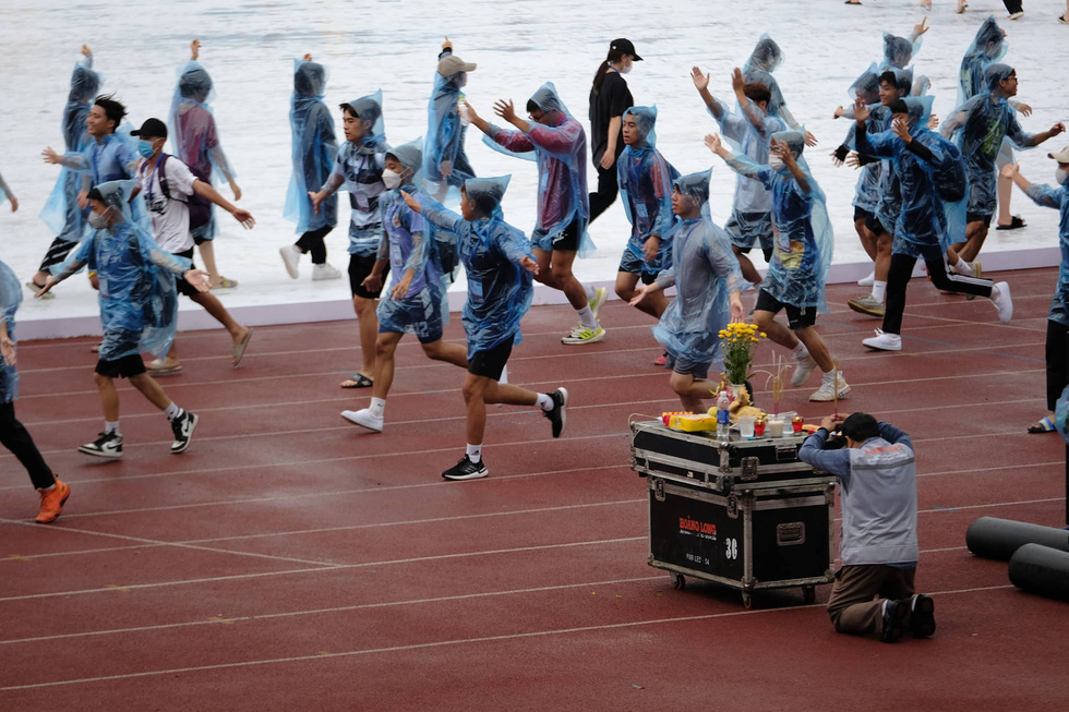 Các vận động viên và tình nguyện viên phải mặc áo mưa  vì trưa mưa khá to ở Hà Nội - Ảnh: NAM TRẦN
