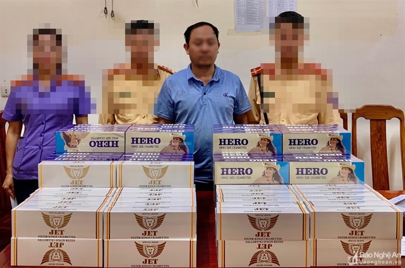 Nguyễn Văn Mười (đứng giữa) và số thuốc lá lậu bị bắt giữ.