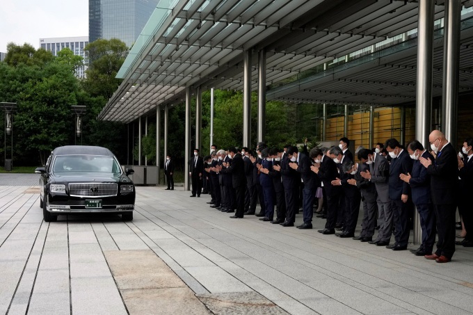 Thủ tướng Nhật Bản Fumio Kishida và các quan chức chính phủ chắp tay cúi đầu khi xe chở thi hài ông Abe đi qua. Ảnh: AFP