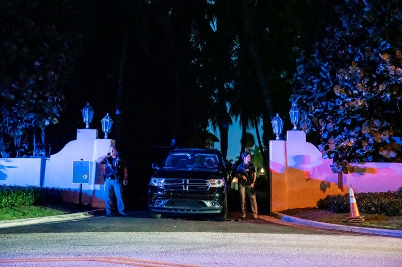 Đặc vụ FBI cầm súng trường đứng bên cạnh ô-tô, gác ở lối vào dinh thự Mar-a-Lago. Ảnh: NYT