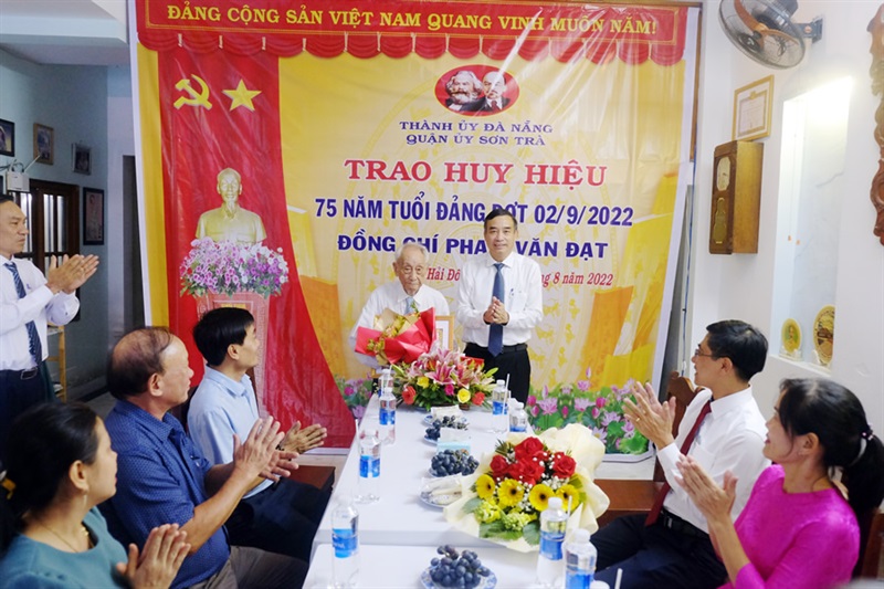Chủ tịch UBND thành phố Lê Trung Chinh trao tặng huy hiệu 75 năm tuổi Đảng cho ông Phạm Văn Đạt.