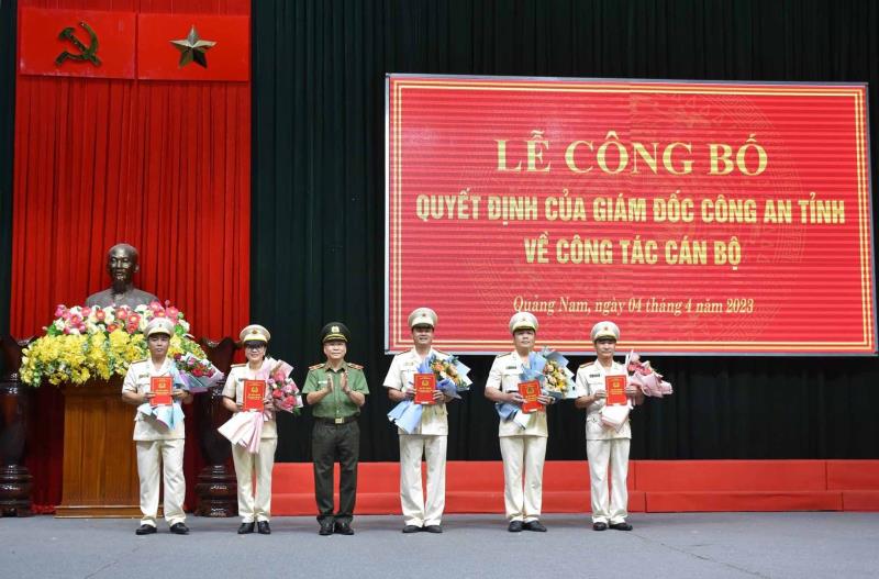 Đại tá Phan Công Bình - Giám đốc Công an tỉnh Quảng Ngãi trao quyết định và tặng hoa chúc mừng Thượng tá Lương Việt Long (phải) và Thượng tá Nguyễn Tấn Thuận.