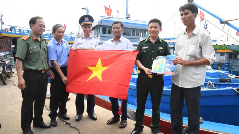 Cảnh sát biển cùng các ngành chức năng tuyên truyền, tặng quà cho ngư dân tại cảng cá Bình Châu.