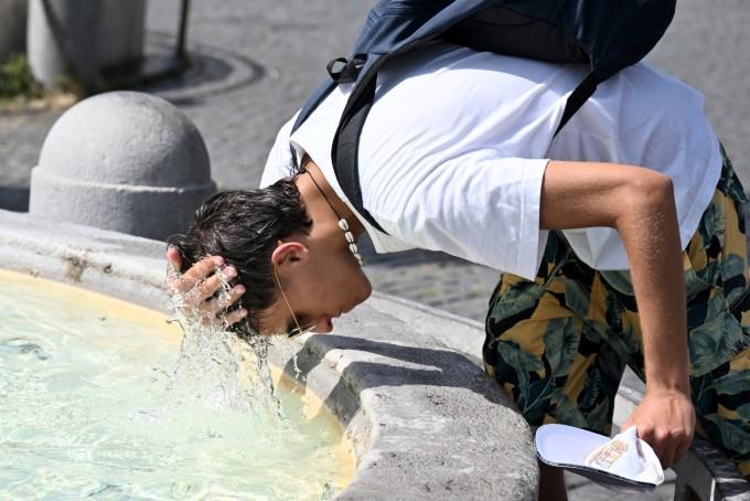 Một cậu bé dội nước lên đầu làm mát ở đài phun nước tại quảng trường Piazza del Popolo ở Rome, Italy, ngày 18-7. Ảnh: AFP