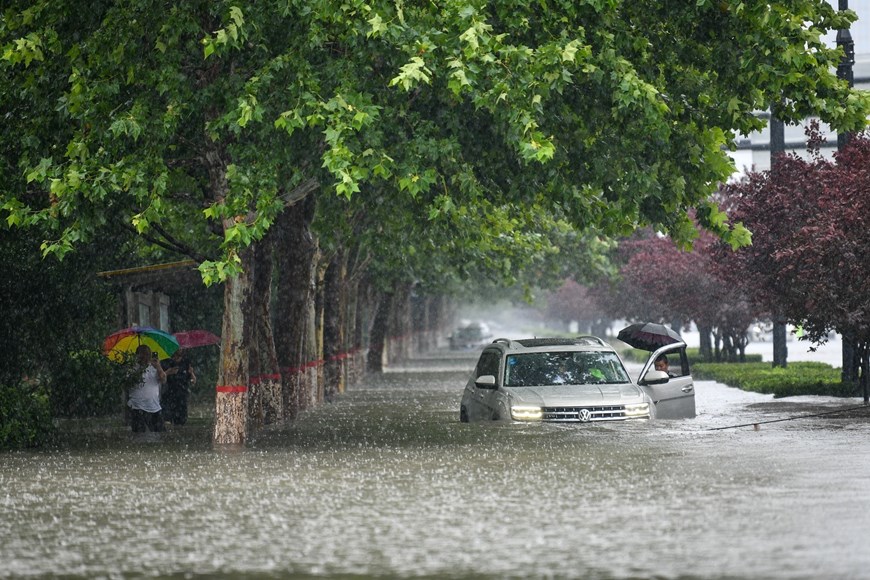 Sơ tán người già khỏi khu vực bị ngập do mưa lũ. (Ảnh: AFP/TTXVN)